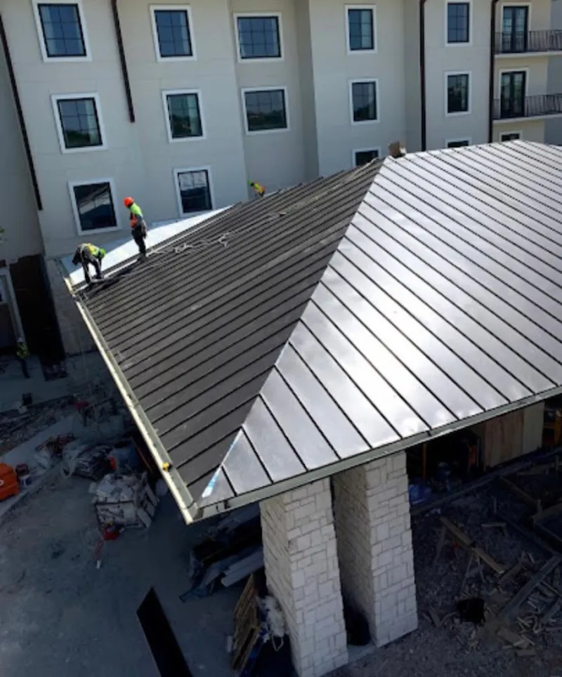 Crew installing standing seam metal roof panels on a commercial project in Deming